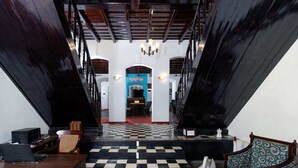 A staircase leading to a dining area with a checkered floor, a chandelier, and a blue sign. - Koder House Heritage Hotel & Spa (Kochi)