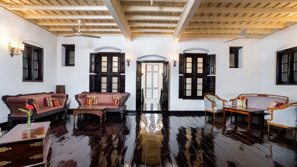 A spacious room with a polished wooden floor, a high ceiling with wooden beams, and a central doorway leading to another area. - Koder House Heritage Hotel & Spa (Kochi)