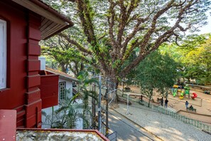 A red building with a staircase leading to a balcony overlooking a playground with slides and a tree. - Koder House Heritage Hotel & Spa (Kochi)