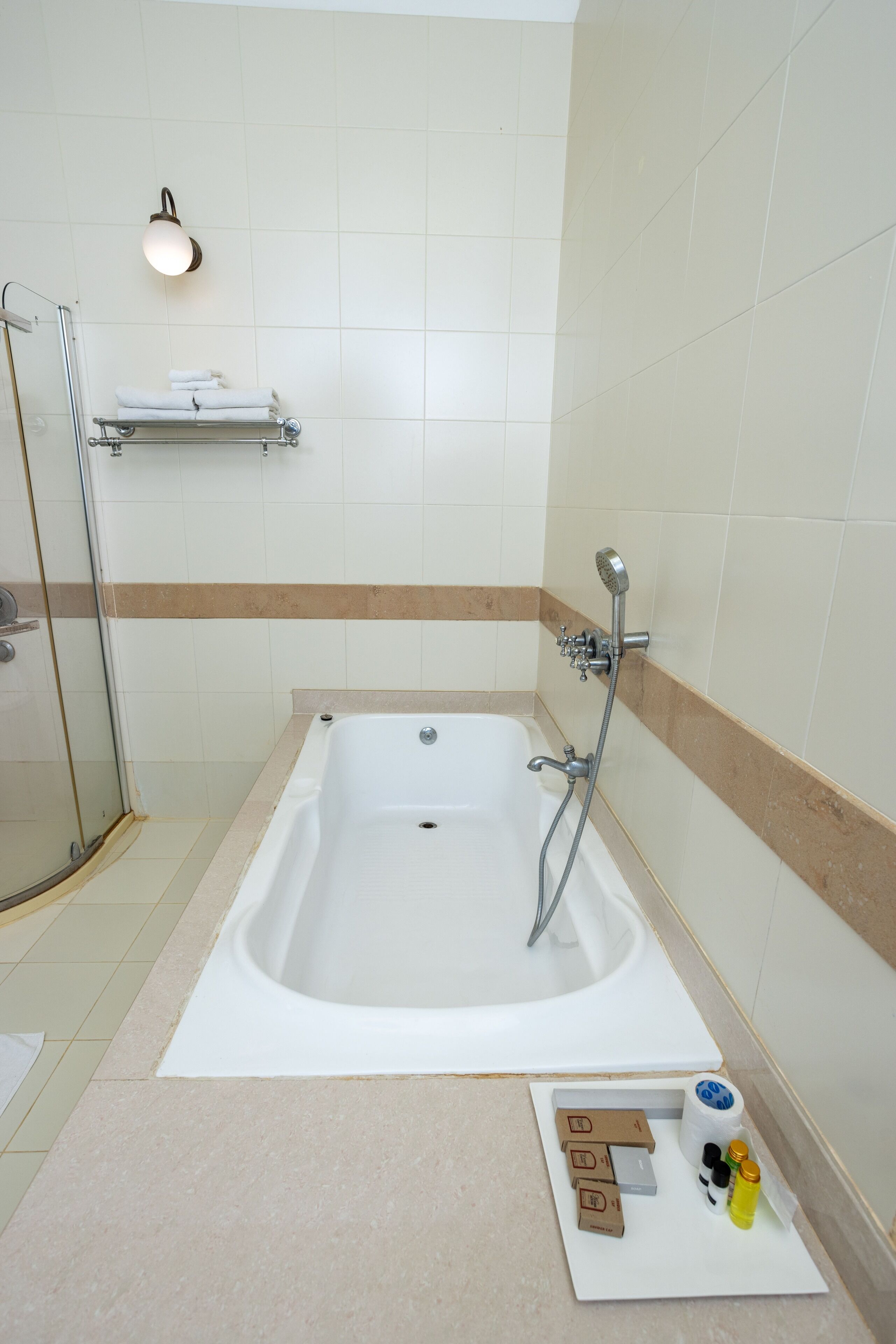 A bathroom with a bathtub, a glass shower enclosure, and a towel rack.