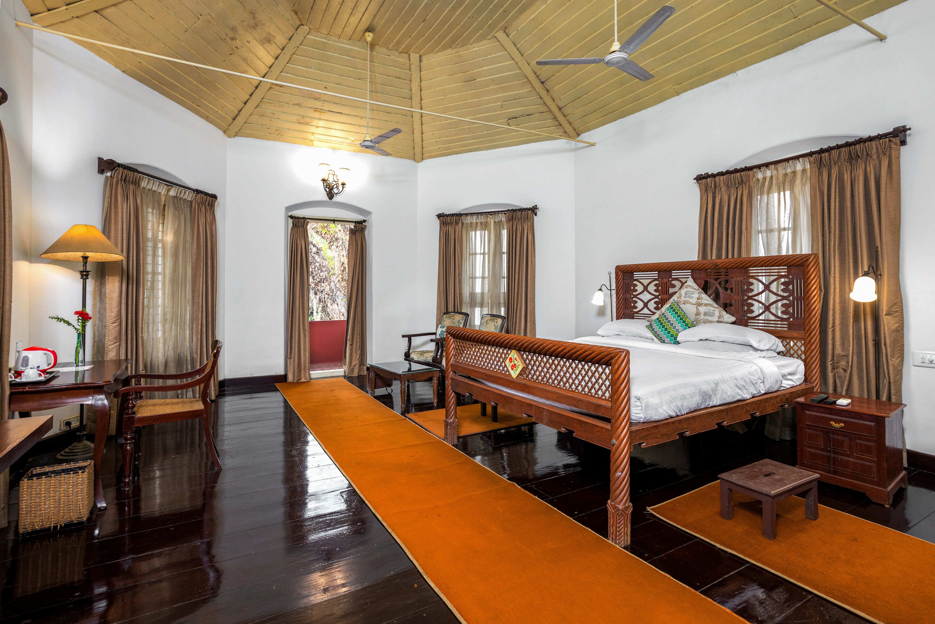 A traditional room with a wooden bed, a desk, and a chair.