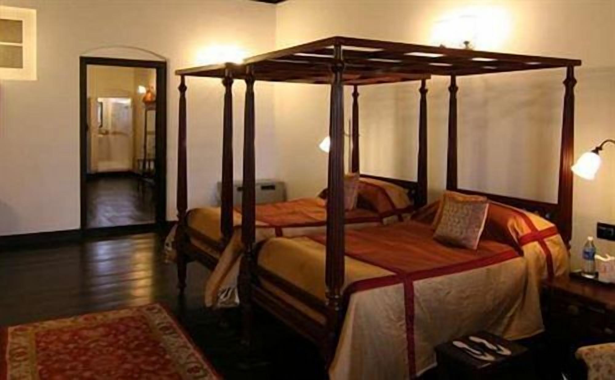 A four-poster bed with a wooden frame and a red and beige bedspread.