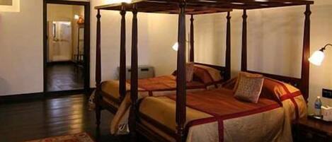 A four-poster bed with a wooden frame and a red and beige bedspread.