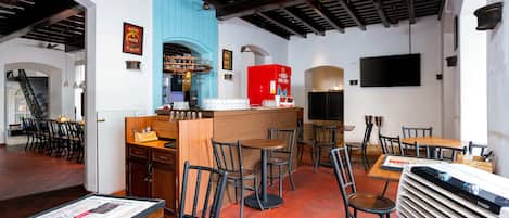 Un interior de restaurante con una zona de bar, varias mesas y sillas, y un tablero de menú.