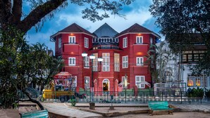 A red building with a balcony and a fountain in front. - Koder House Heritage Hotel & Spa (Kochi)