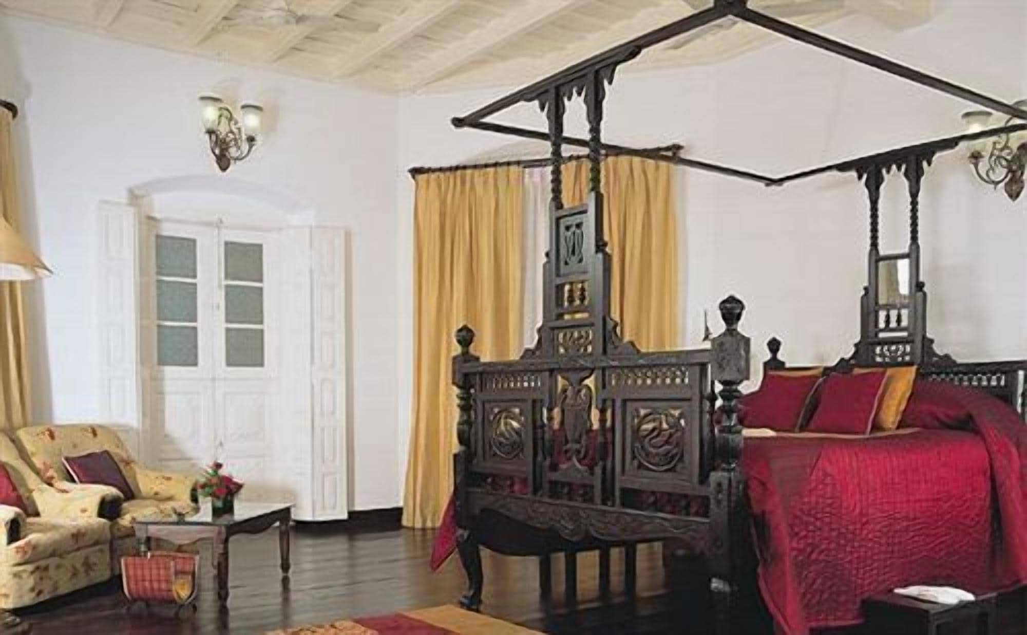 A traditional room with a four-poster bed, a sofa, and a small table.