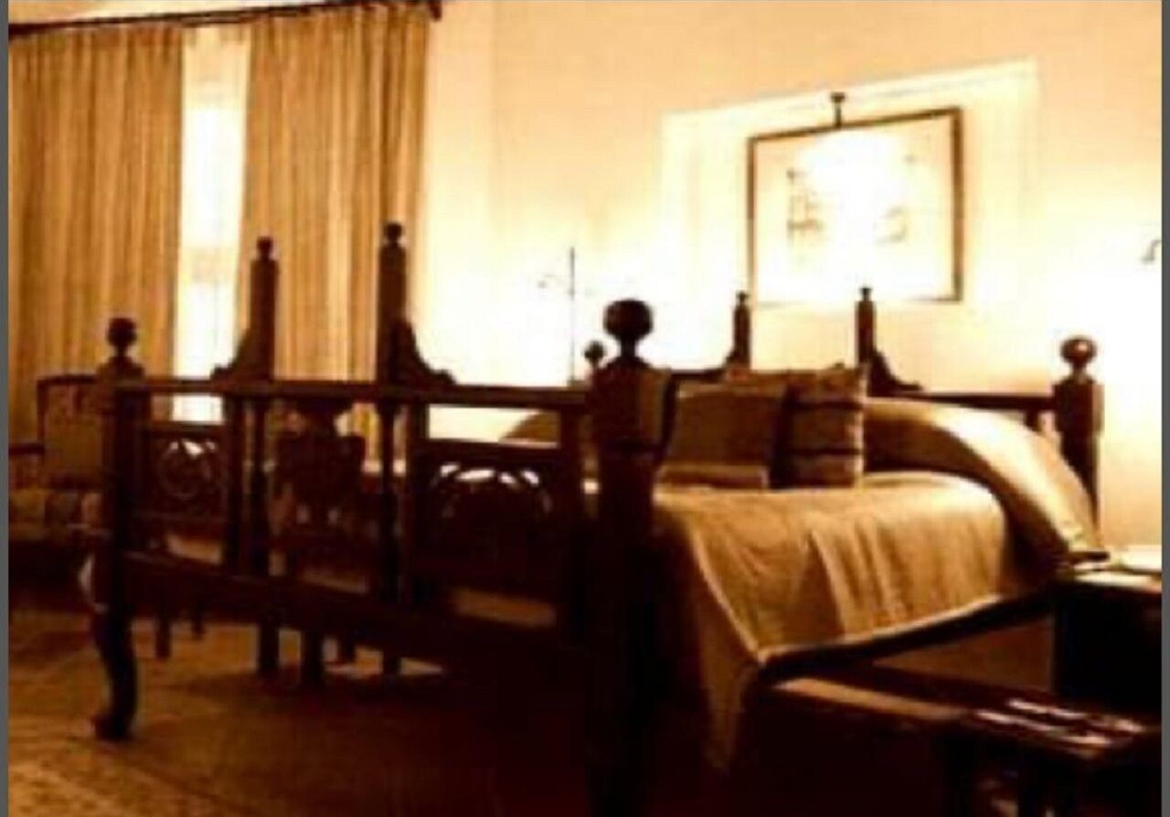 A dimly lit hotel room with a bed, a chair, and a desk.