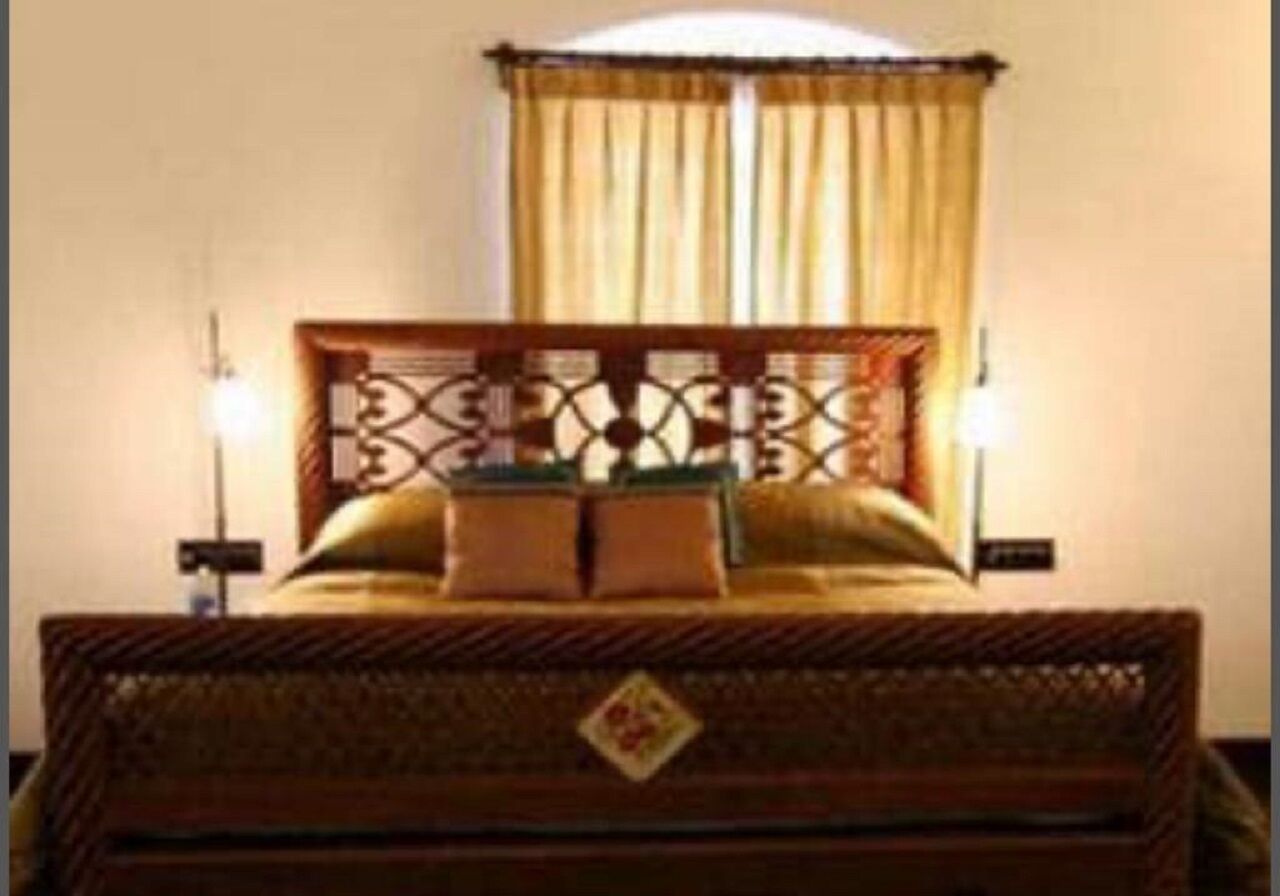 A bed with a wooden headboard and a decorative pattern, a bedside table, and a lamp.
