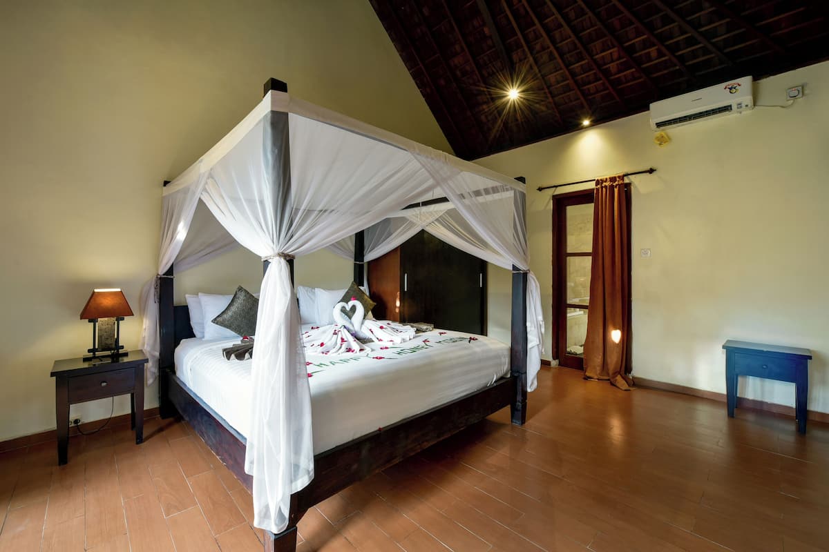 A four-poster bed with a canopy, a bedside table with a lamp, and a small blue nightstand.