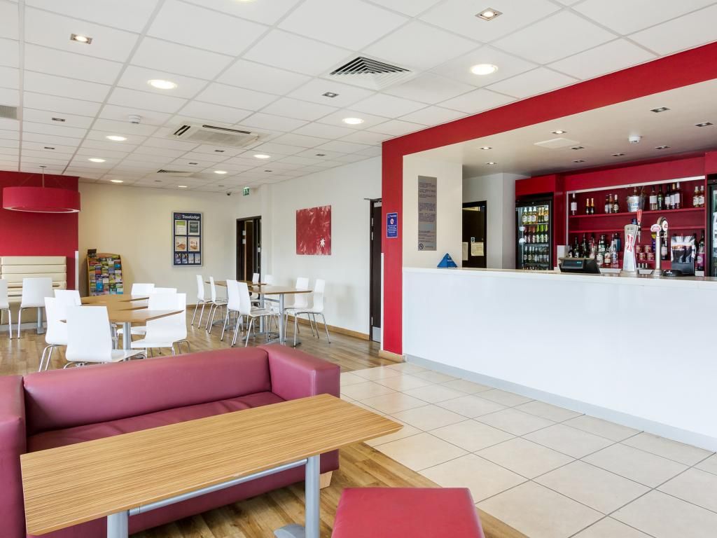 A modern interior with a red and white color scheme, featuring a reception area, seating arrangements, and a bar counter.