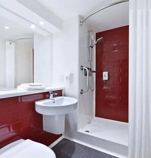 A modern bathroom with a white sink, a mirror, and a red-tiled shower enclosure. - Travelodge Morecambe (Morecambe)