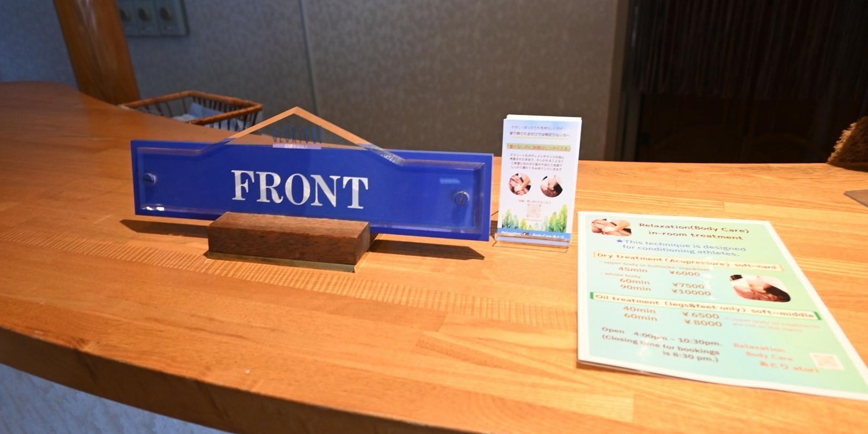 Un comptoir d’accueil en bois, sur lequel est apposée une enseigne bleue portant l’inscription « ACCUEIL », et une brochure décrivant les services proposés.