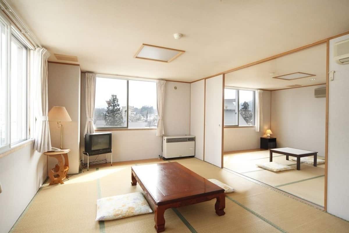 A traditional Japanese room with tatami flooring, a television, a heater, and a small table.