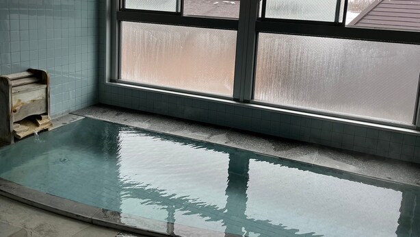 Una piscina con piso de baldosas y una ventana con vidrios esmerilados.