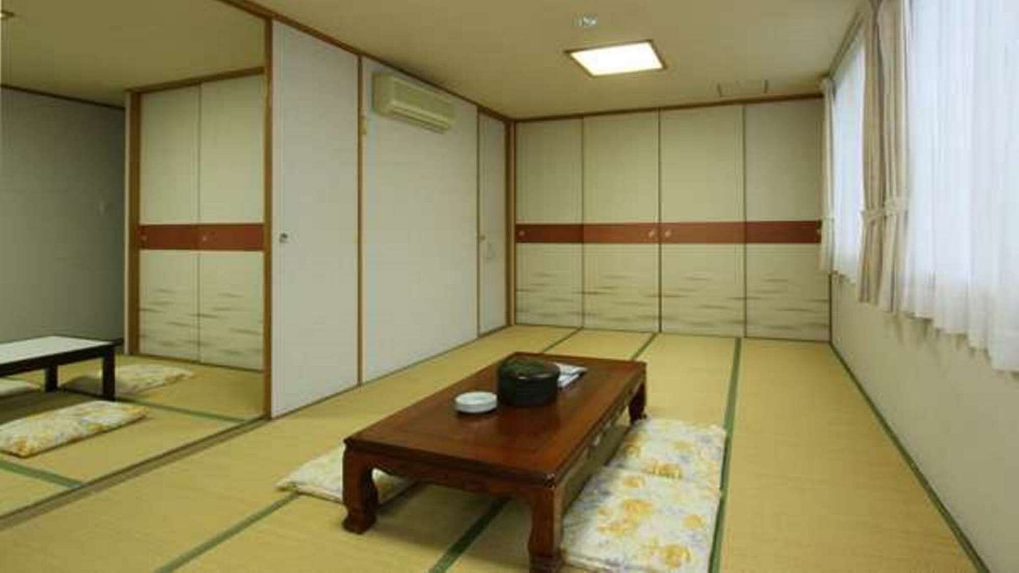 Een kamer met tatami matten, een houten tafel, een bank en schuifdeuren.