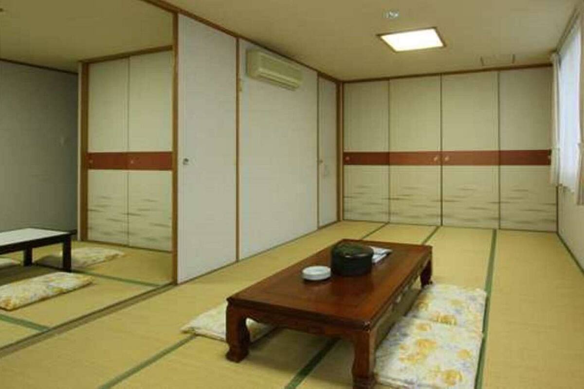 Habitació amb esteimat de tatami, taula de fusta, una banca i portes corredisses.