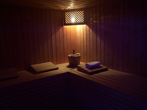 A sauna room with wooden benches, a bucket, and a towel. - Hotel Podravina (Koprivnica)
