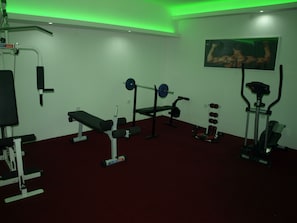 Un gimnasio con diverso equipo de ejercicio, incluyendo una banca, una estructura para sentadillas y una banca de pesas.