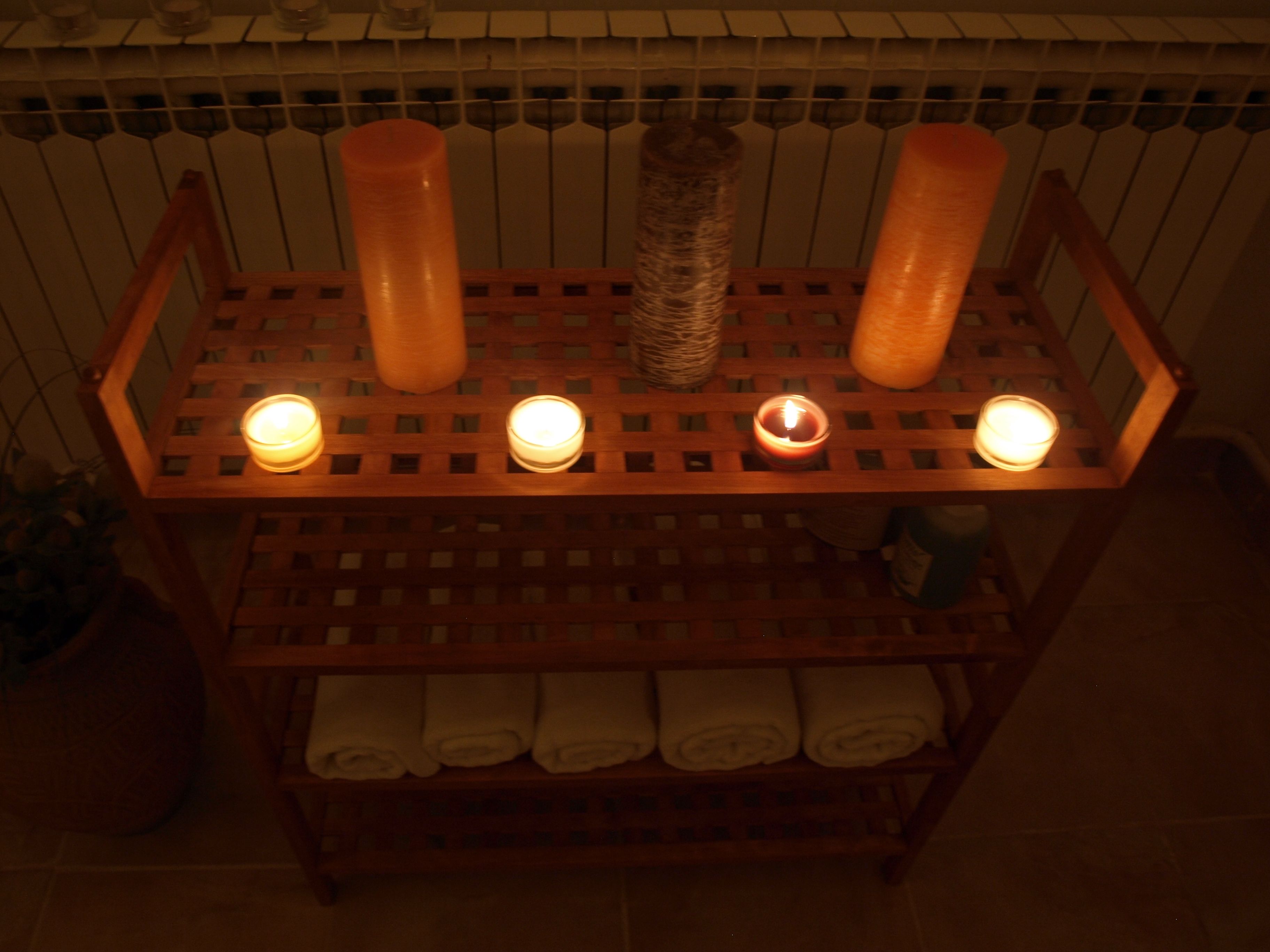 Une étagère en bois avec des bougies et des serviettes enroulées.