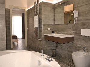 A modern bathroom with a large bathtub, a vanity with a mirror, and a bidet. - Palazzo Ducale Suites (Monreale)