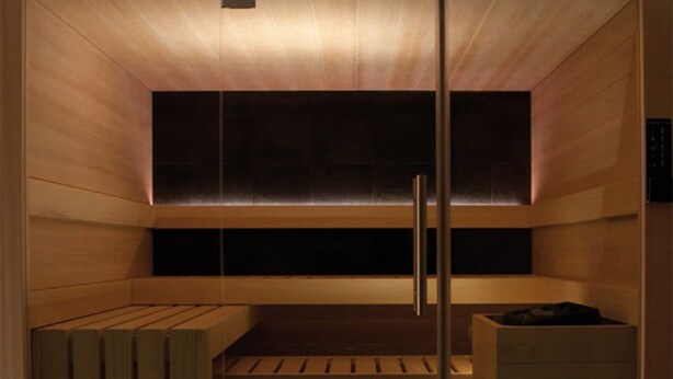 A sauna room with wooden walls, a bench, and a seating area.