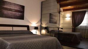 A bedroom with a large bed, bedside tables, a mirror, and a wall-mounted artwork.