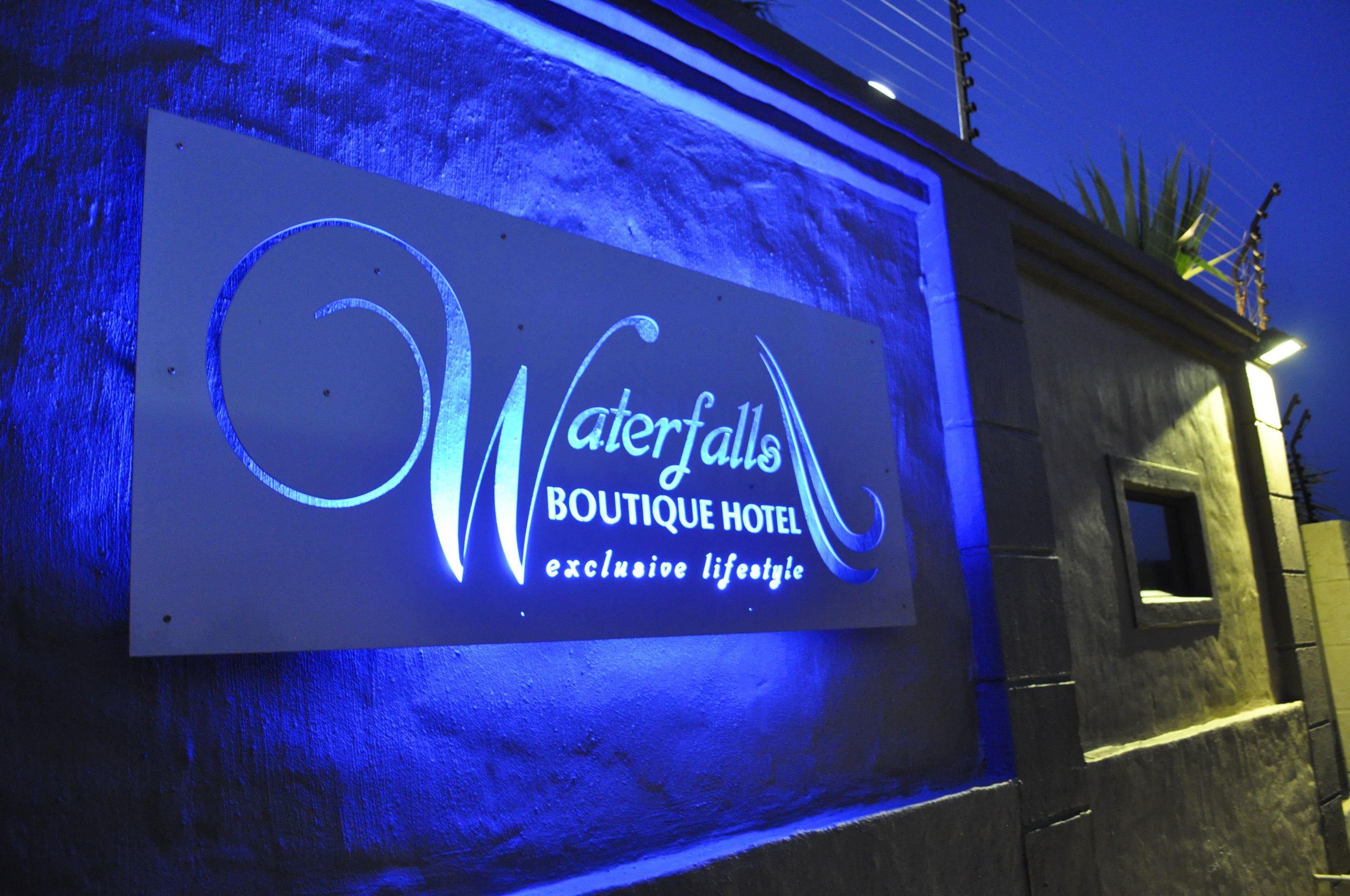 A sign for 'Waterfalls Boutique Hotel' with a modern design and illuminated lettering.