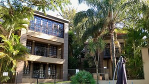 A two-story building with a swimming pool, outdoor seating, and a bench. - Waterfalls Boutique Hotel (Pretoria)