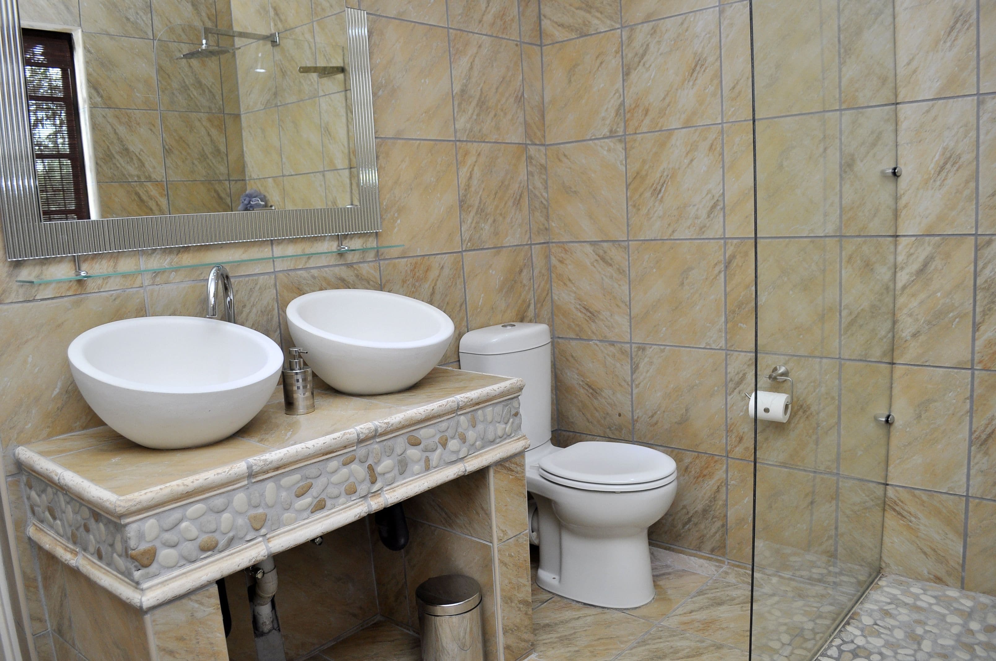 Een badkamer met twee wastafels, toilet en douche.
