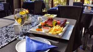 A dining table with a plate of food, a glass of water, and a napkin. - Waterfalls Boutique Hotel (Pretoria)