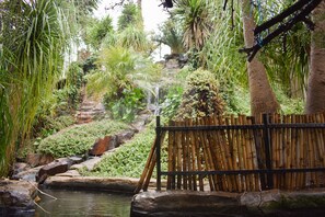 A bamboo fence, a small waterfall, and lush greenery in a garden setting. - Waterfalls Boutique Hotel (Pretoria)