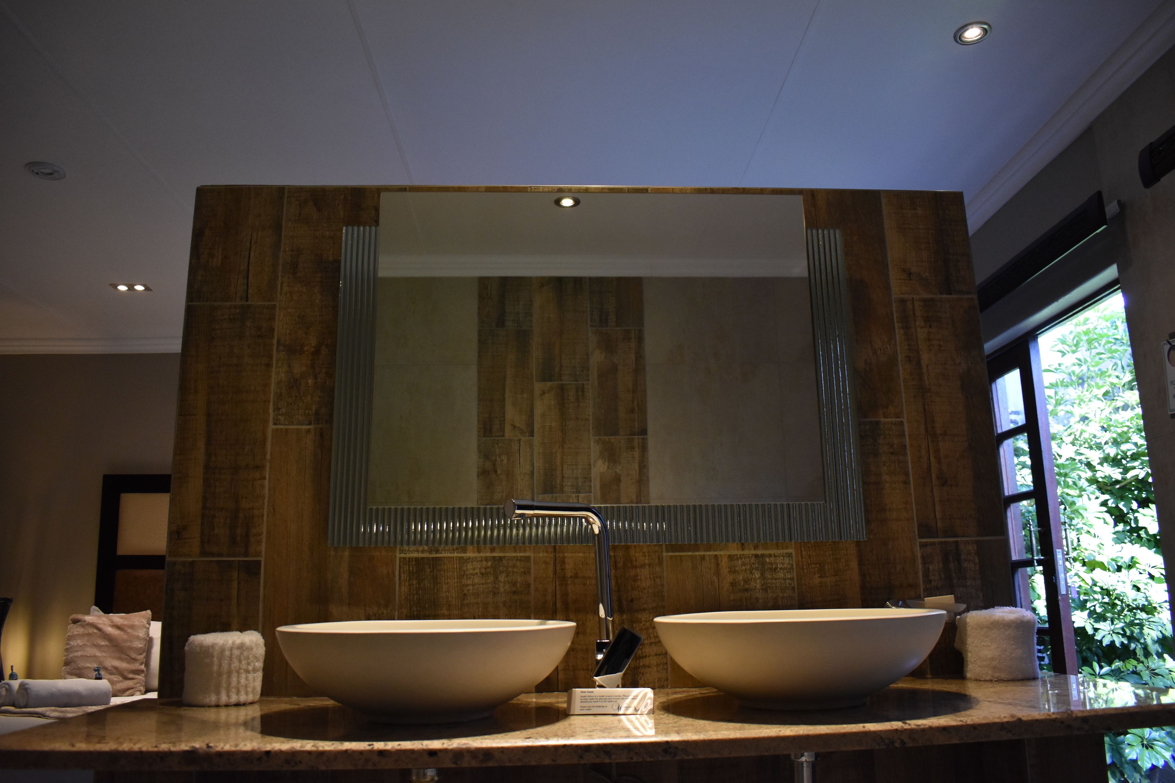 Une salle de bain avec deux grands lavabos, un miroir et une fenêtre.