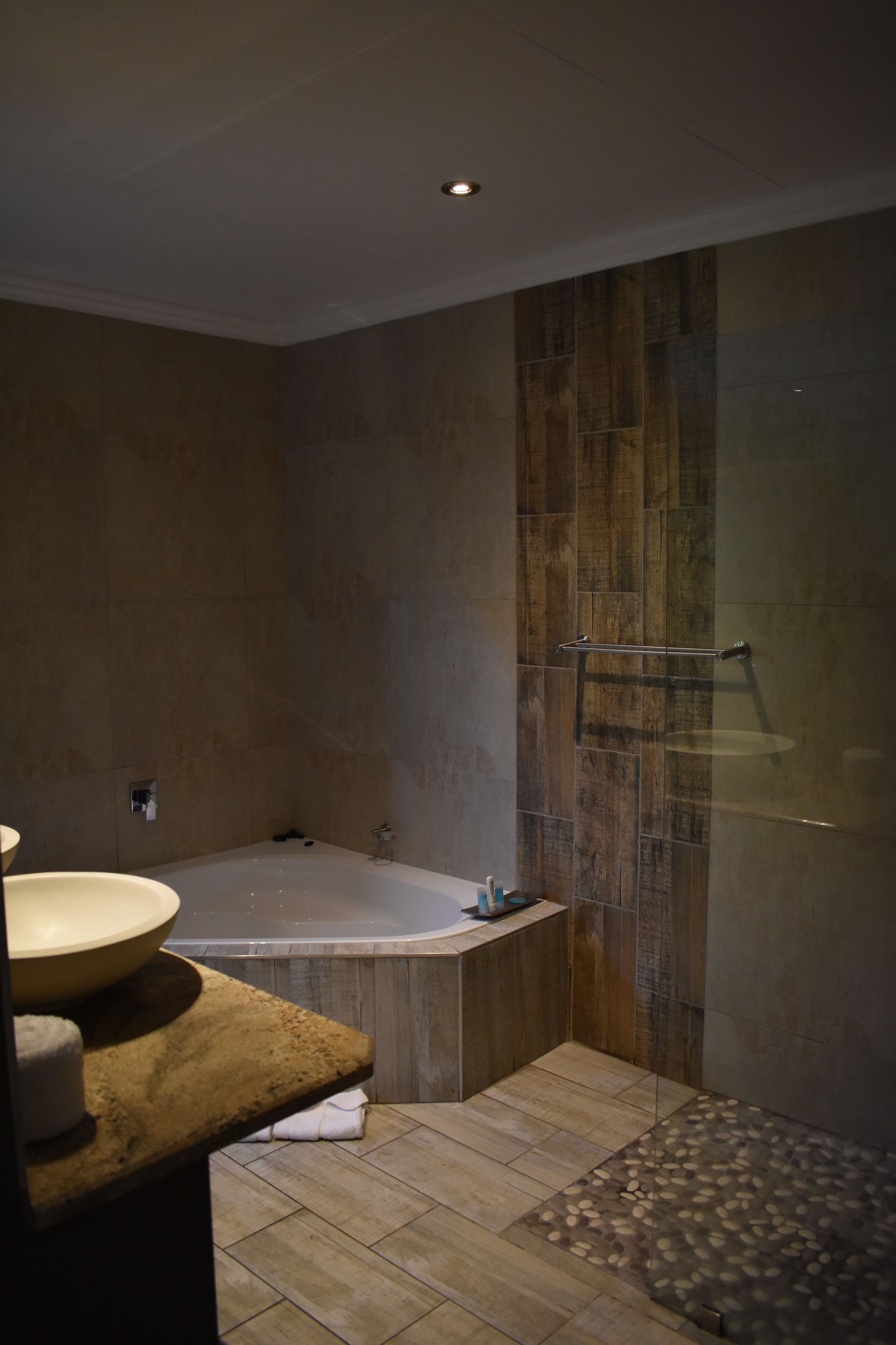 A modern bathroom with a freestanding bathtub, a glass shower enclosure, and a wooden vanity.