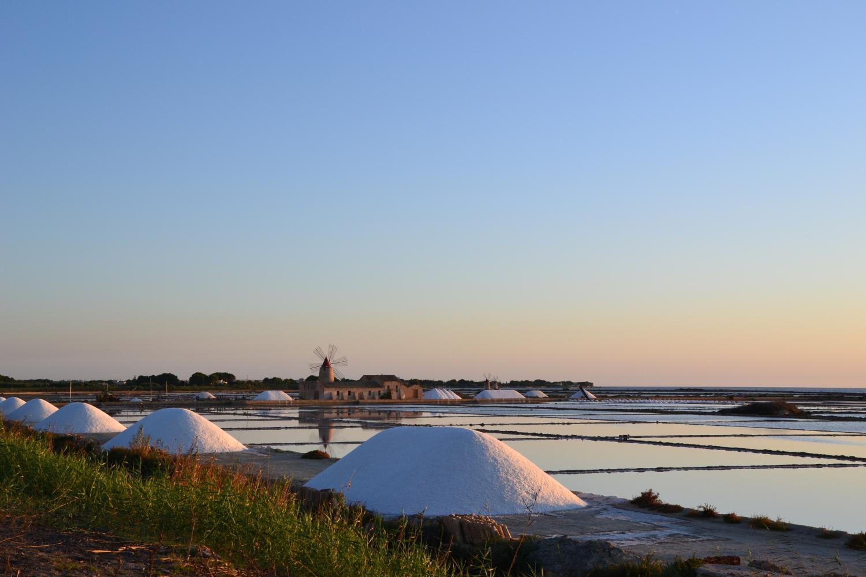 A coastal landscape with salt pans and a windmill.