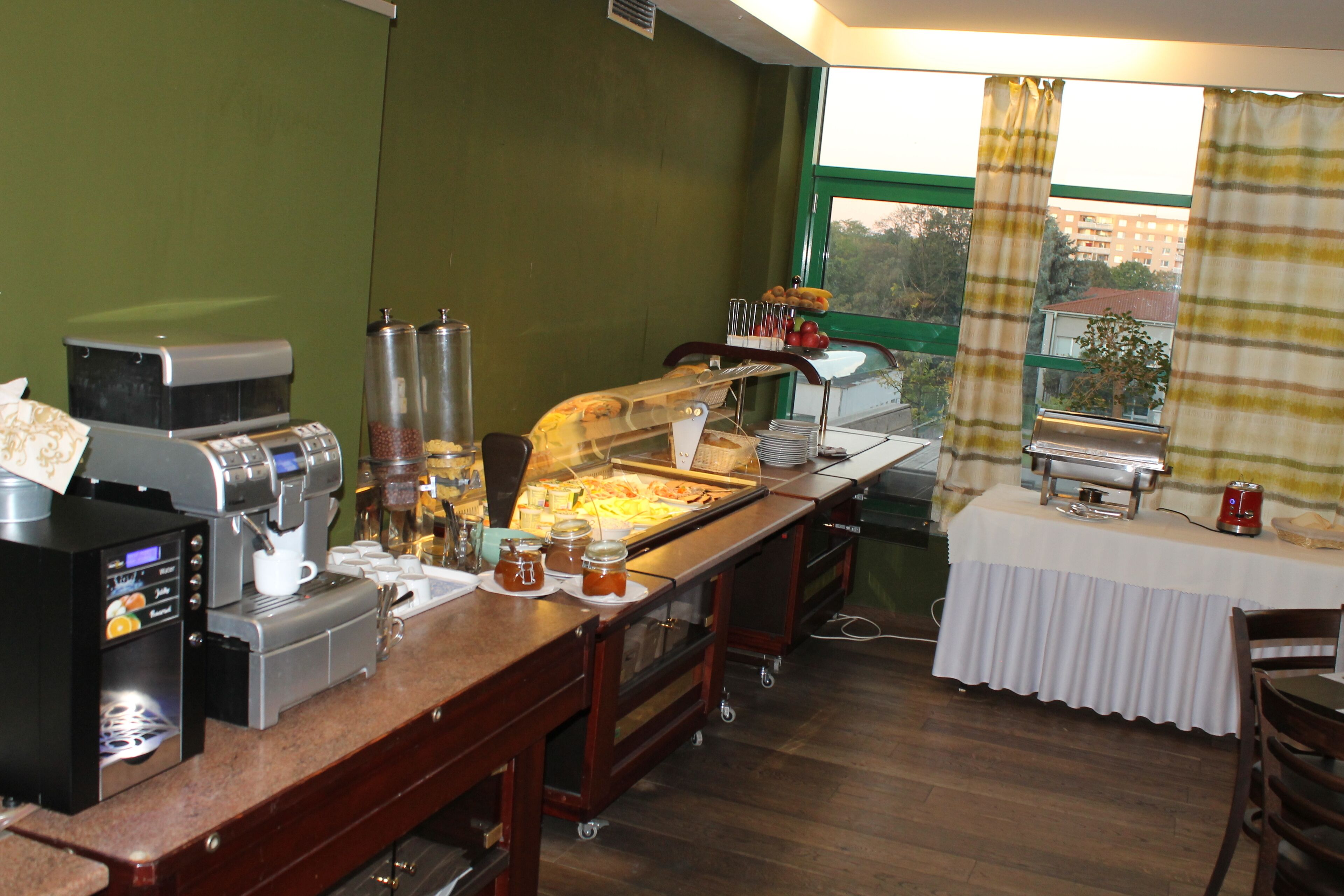 Dispositiu de bufet amb una màquina de cafè, aliments i una finestra amb cortines.