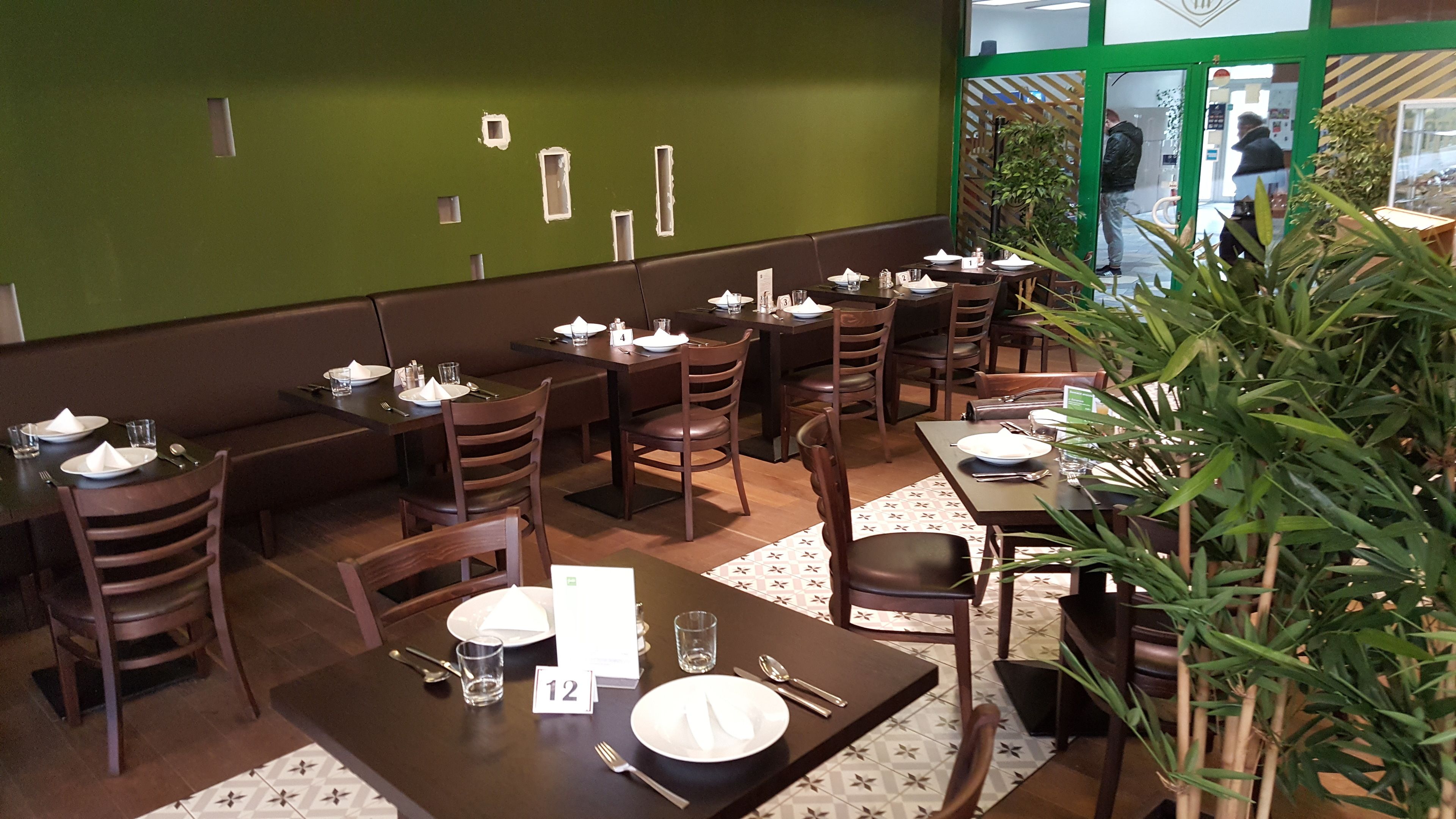 Un restaurante con cabinas y mesas, cada conjunto con platos, cubiertos y vasos.