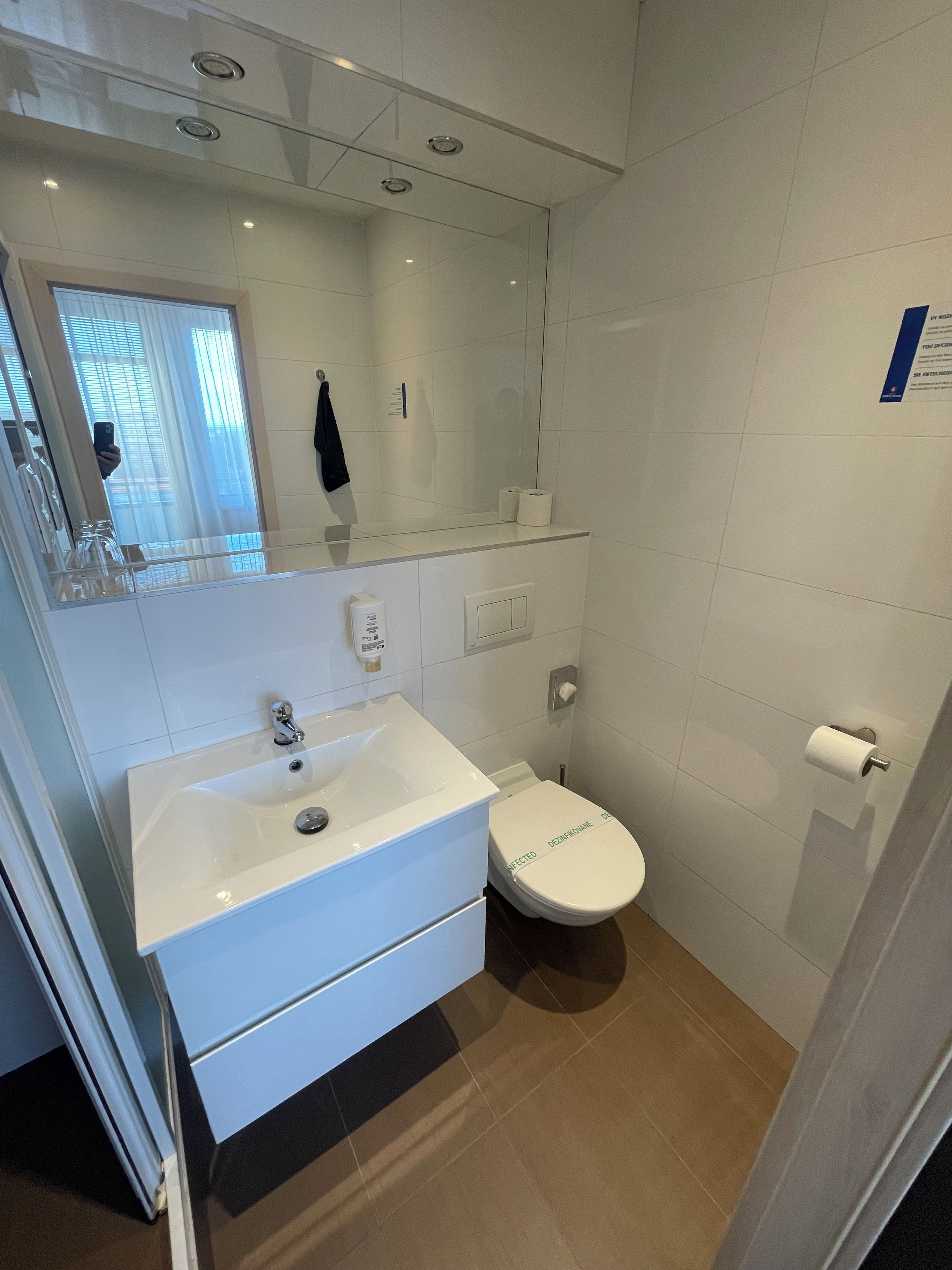 A modern bathroom with a white sink, toilet, and mirror.
