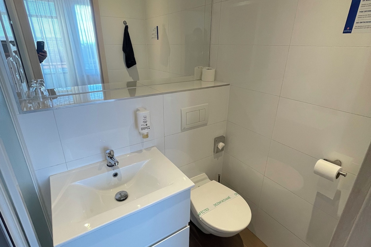 A modern bathroom with a white sink, toilet, and mirror.