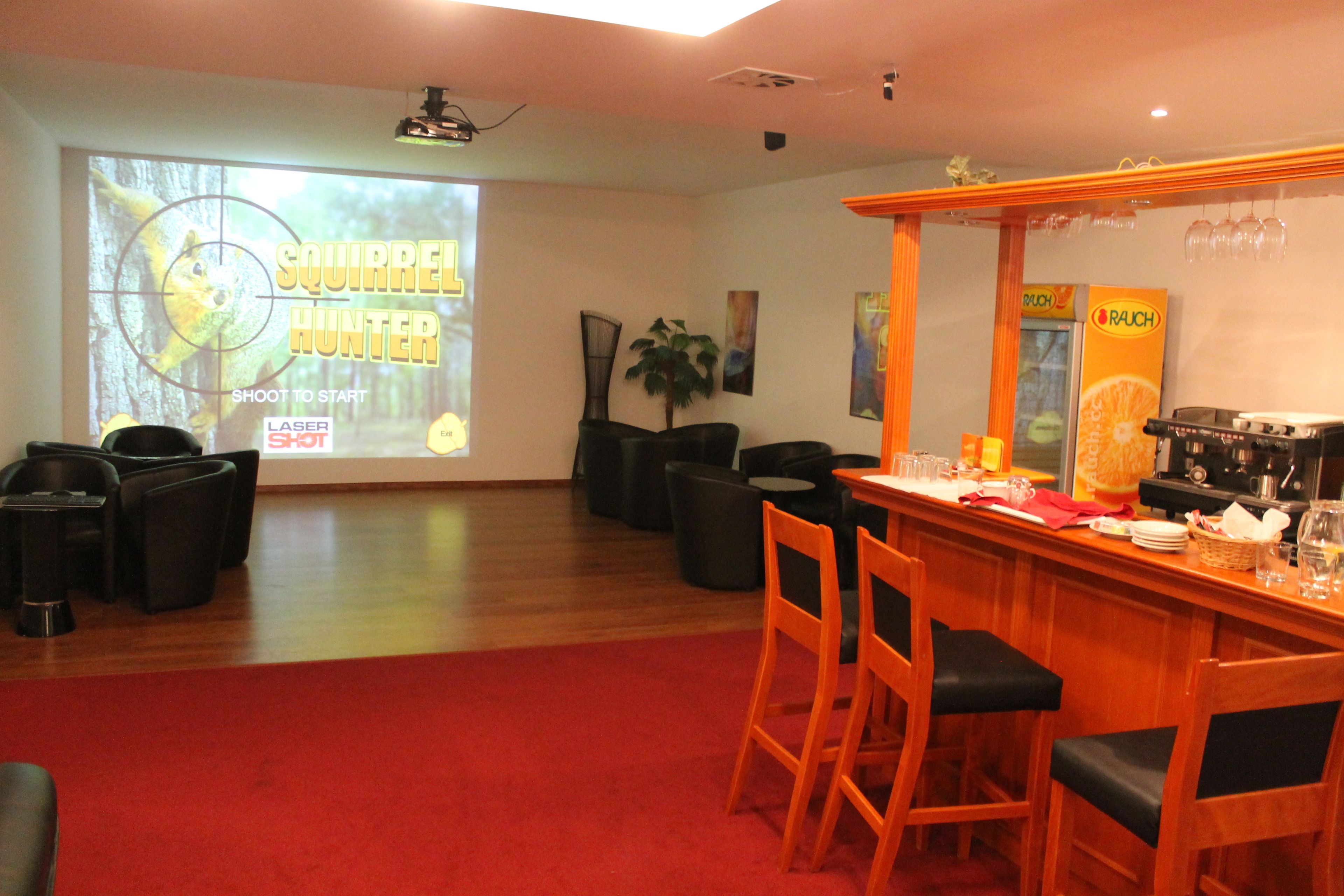 A bar area with wooden chairs and a red carpet.