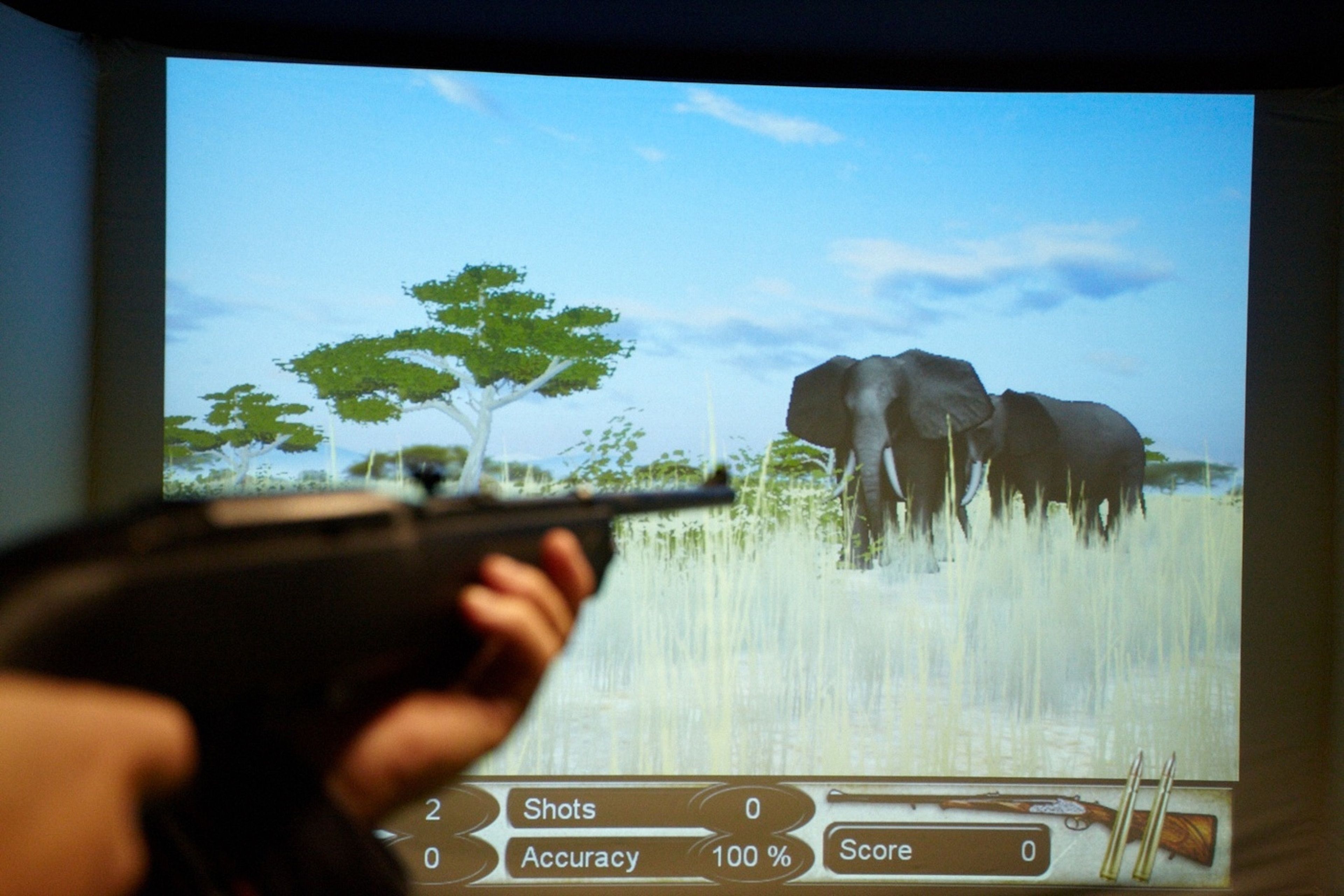 A video game interface with a gun aimed at elephants, displaying shots, accuracy, and score.