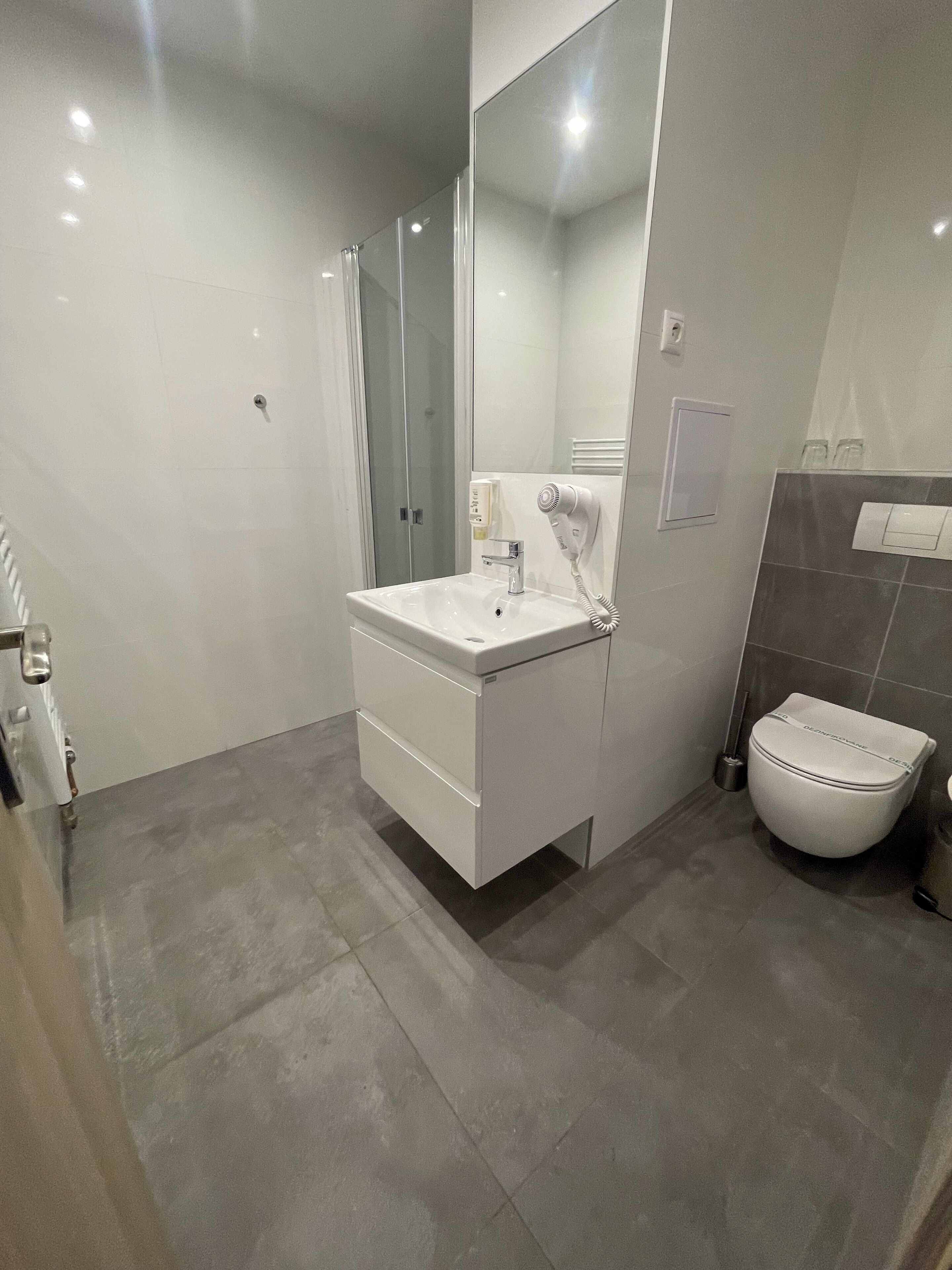 Un baño moderno con tocador blanco, cabina de ducha de vidrio y inodoro.