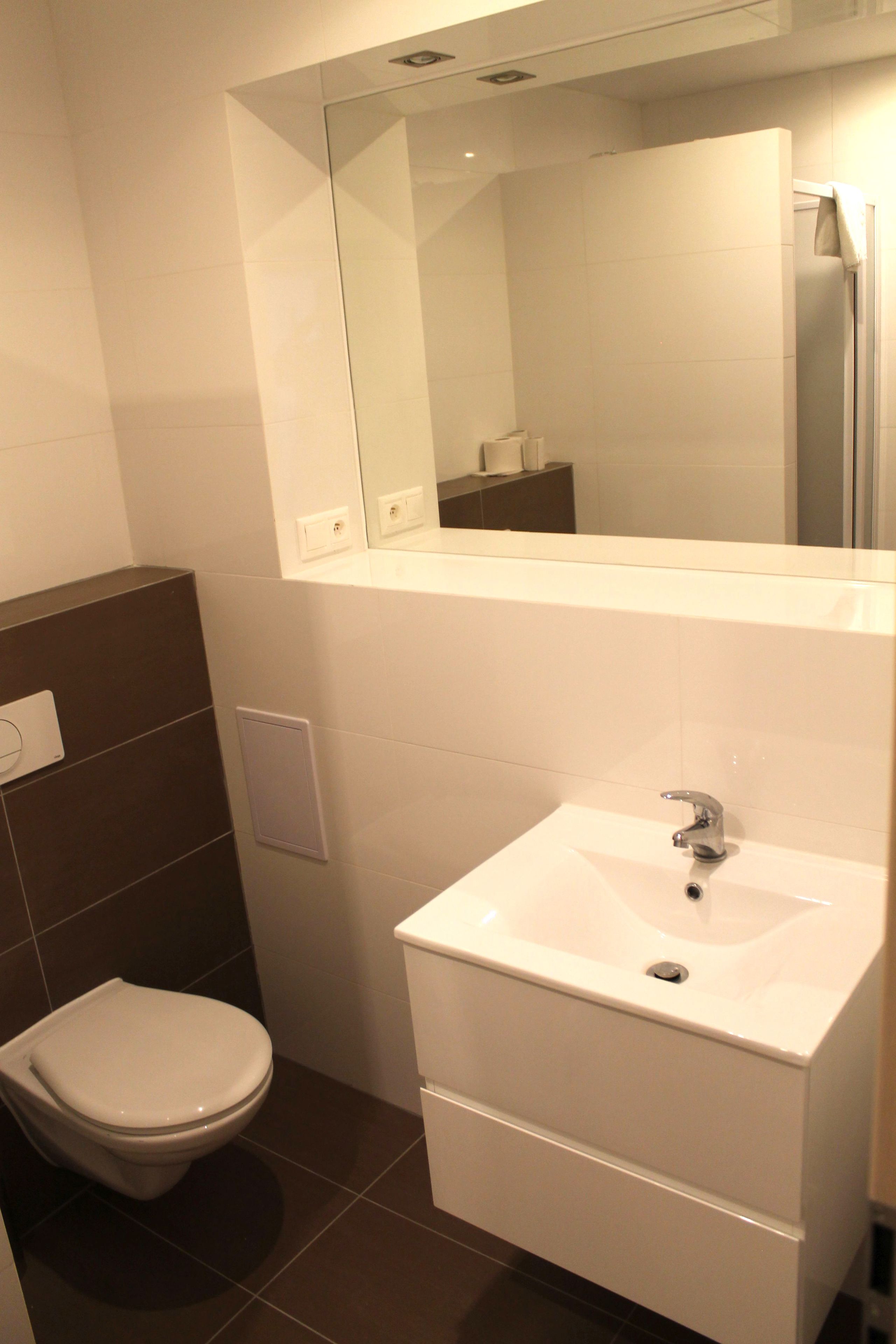 Un baño moderno con inodoro, lavamanos y espejo.
