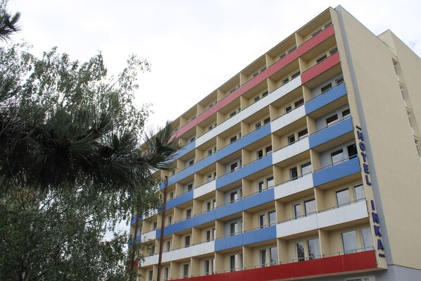 A multi-story hotel with a flat facade, balconies on each floor, and a sign indicating it is a hotel.