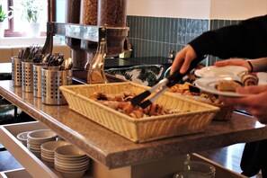 Guests can enjoy a wide selection of food at the buffet, featuring a coffee machine and various serving utensils.