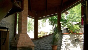 A stone fireplace with a brick chimney, a wooden bench, and a potted plant. - Rem's Pension (Rasnov)