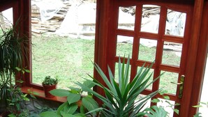 A conservatory with a stone floor, wooden railing, and various potted plants. - Rem's Pension (Rasnov)