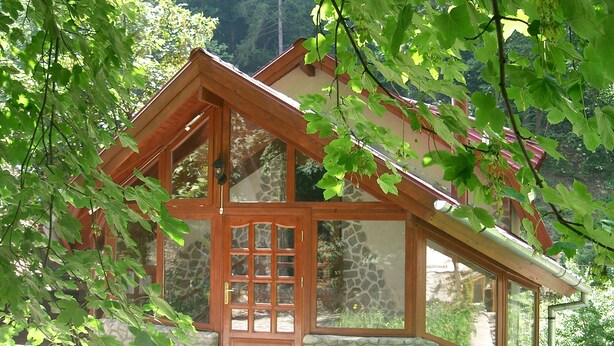 A wooden house with a stone foundation, large windows, and a wooden door. - Rem's Pension (Rasnov)