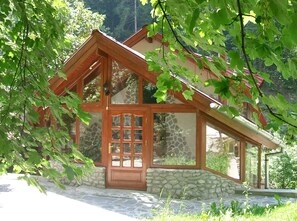 A wooden house with a stone foundation, large windows, and a wooden door.