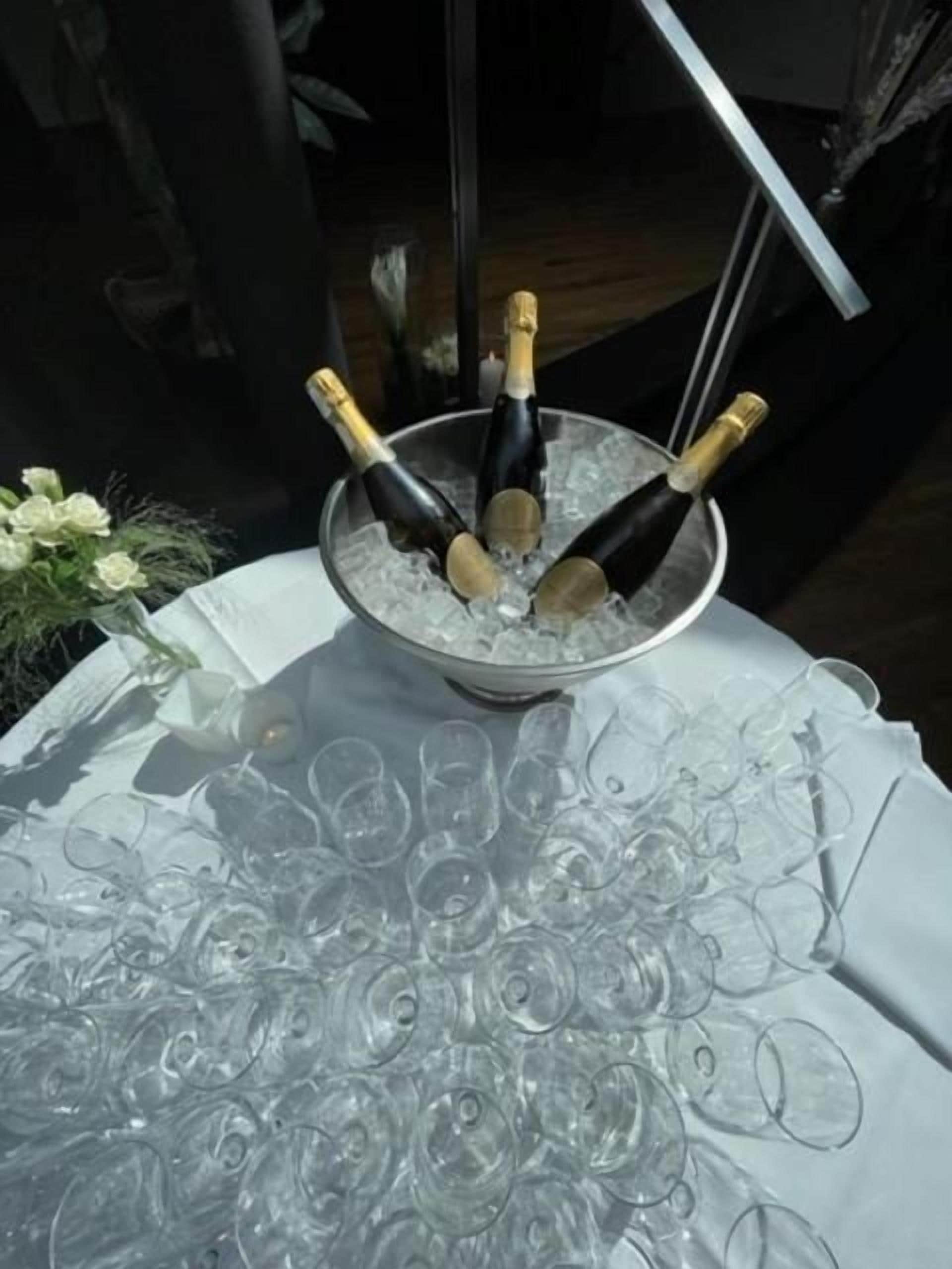 A table with a bowl containing champagne bottles and glasses.