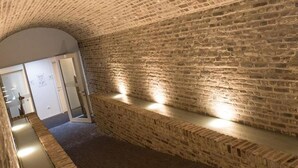 Un pasillo con pared de ladrillo y un banco.